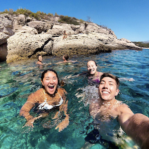 Three students take a selfie in bright blue waters
